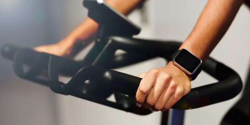 Person wearing a smartwatch while exercising on gym equipment, showcasing fitness tracking and health monitoring features.