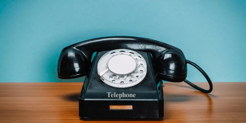 Close-up of an old rotary telephone with the word 'Telephone' printed on the front, highlighting vintage communication technology.